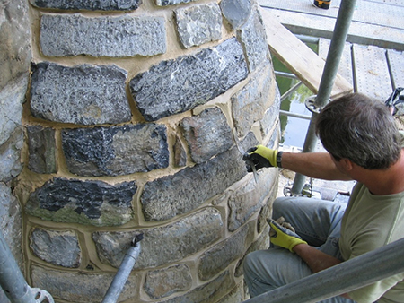 Mason repointing stone buttress on bridge